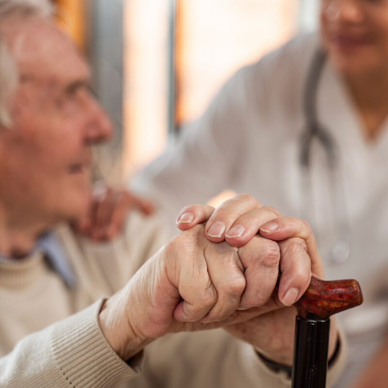 Foto sobre Geriatria: Uma médica conversando com um senhor idoso que está segurando uma bengala
